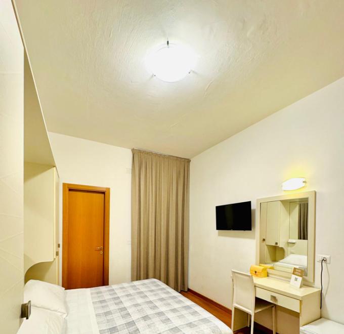 Cozy, bright room with a double bed, desk, and TV.