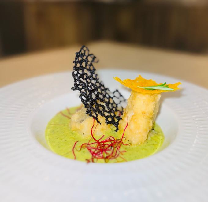 Elegant dish with green sauce, crispy decorations, and vibrant red strands.